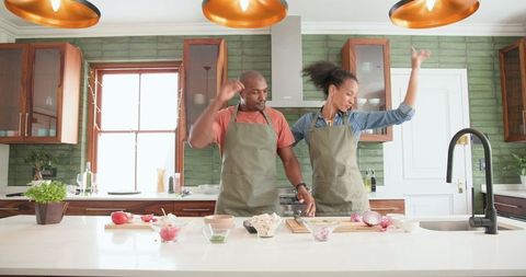 Couple Joyfully Dancing While Preparing Meal in Modern Kitchen