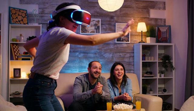 Friends cheering while playing virtual reality game during cozy movie night