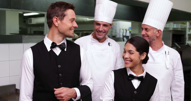 Chefs and waiters smiling and discussing work, promoting teamwork and friendliness. Ideal for hospitality industry promotions, teamwork concepts, and food service advertisements.