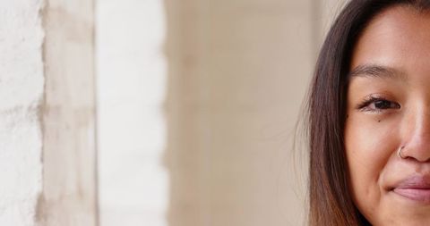 Asian Woman with Nose Ring Gazing Calmly Against Minimalist Background