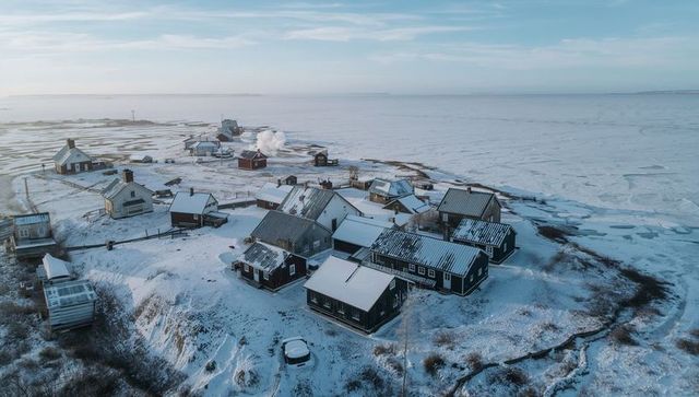 Remote Arctic Coastal Village with Snow-Covered Wooden Cottages and Smoking Chimneys