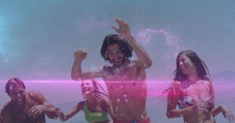 Friends jumping and splashing on sunlit beach with lens flare and carefree summer energy