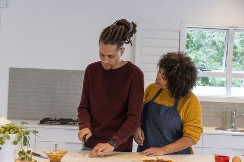 African american couple baking dough together in sunlit modern kitchen for cozy baking