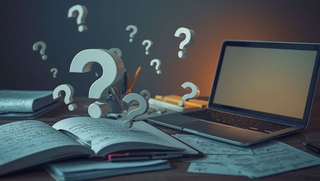Question Marks Above Desk with Laptop and Notebook