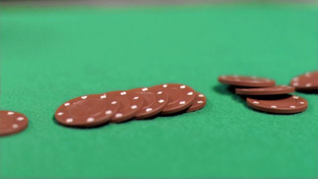 Brown poker chips falling in super slow motion on a green poker table. This video captures the dynamic action and anticipation in a poker game. Great for illustrating casino and gambling themes, poker game tutorials, or promotional materials for casinos and gaming events.