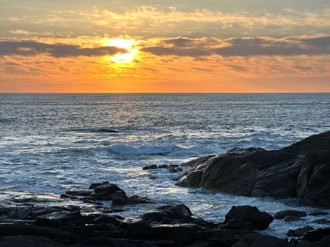 Stunning sunset over ocean with gentle beach waves and rocky shore