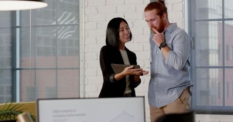 Diverse Professionals Collaborating on Tablet in Modern Office