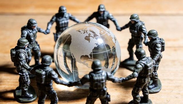 Toy soldiers holding hands around glass globe representing global security and unity