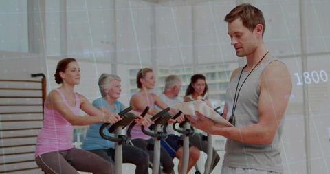 Gym Trainer Overseeing Fitness Class with Participants on Exercise Bikes