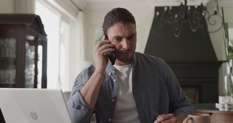 Focused Man on Smartphone Call While Working at Home