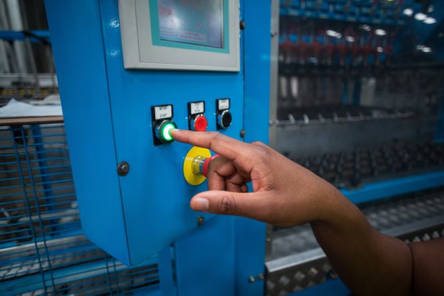 Hands of factory worker pressing a green button on the control board in factory