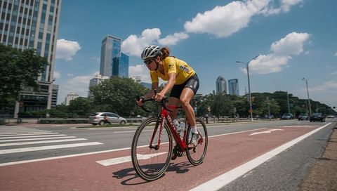 Female Cyclist Racing in Urban Bike Lane Wearing Yellow Jersey on Red Road Bike