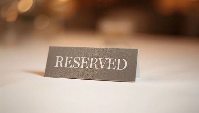 Reserved sign resting on white tablecloth at banquet with warm bokeh lights