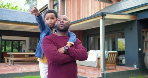 African american father carrying son pointing on modern patio embracing family bonding and parenting