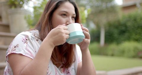 Woman Enjoying Coffee Outdoors in Peaceful Garden Setting