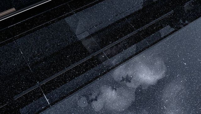 Abstract urban reflections on glossy glass facade with rain flecks and blurred silhouettes