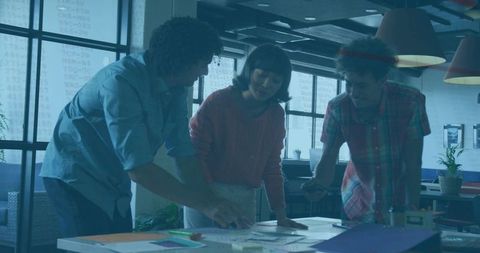 Team collaborating around table reviewing documents in modern open-plan workspace