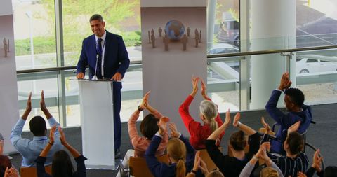 Business seminar speaker receiving applause from audience