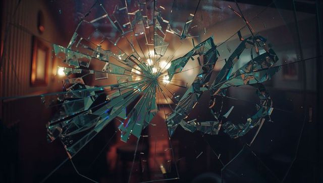 Shattering Glass Spiral Over Dim Hallway with Warm Chandelier Glow