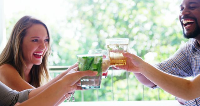 Group of friends raising glasses during a cheerful toast outdoors. Great for depicting camaraderie, celebration, relaxation, and outdoor social gatherings.