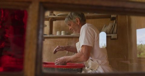 Senior artisan making pottery in workshop, embracing creativity and tradition