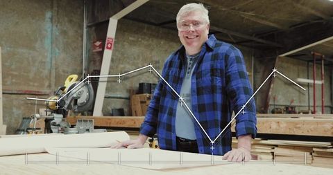 Smiling woodworker wearing plaid shirt and safety glasses at bench with line-chart overlay