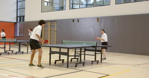 Students Engaging in Energetic Table Tennis Match at School