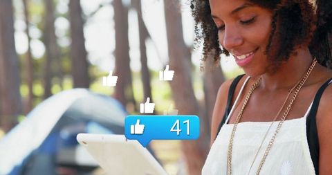 Woman Using Tablet at Forest Campsite with Social Media Icons