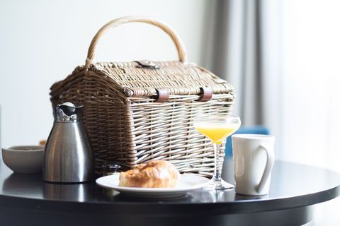 Breakfast picnic basket with drink and pastries on table