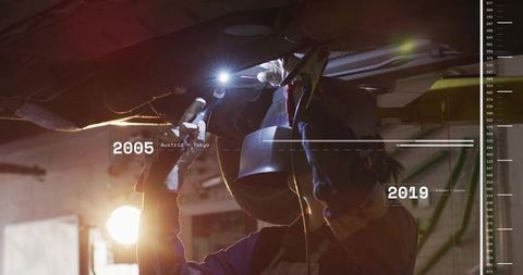 Female Mechanic Inspecting Undercarriage Under Lift with Torch and Welding Helmet
