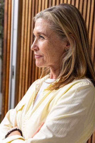 Elegant Senior Woman Contemplating by Window in Minimalist Space