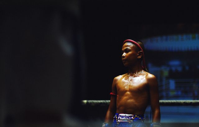 Young Muay Thai athlete standing in boxing ring, focused and prepared. Ideal for sports adverts, youth boxing promotion, Thai culture stories, martial arts training campaigns, or athletic magazines.