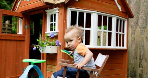 Curious Baby Boy Exploring Backyard Playhouse