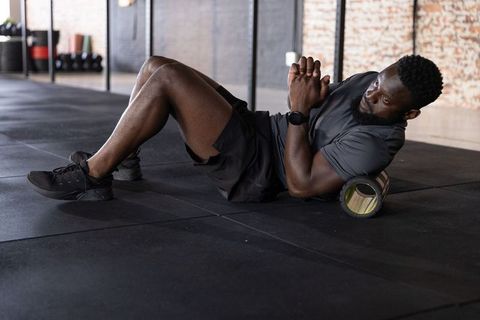 African american man using foam roller for myofascial release and athletic recovery