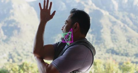 Man raising hand and crossing arms on mountain balcony with neon augmented jaw overlay
