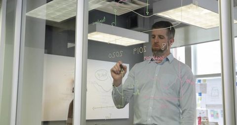 Business professional analyzing data on glass partition