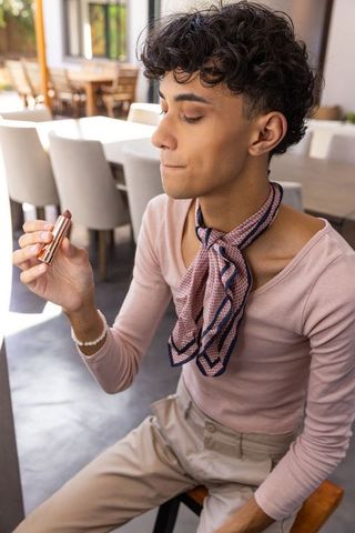 Man holding lipstick in modern dining space, epitome of elegance