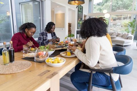 African american friends sharing meal around sunlit modern wooden dining table