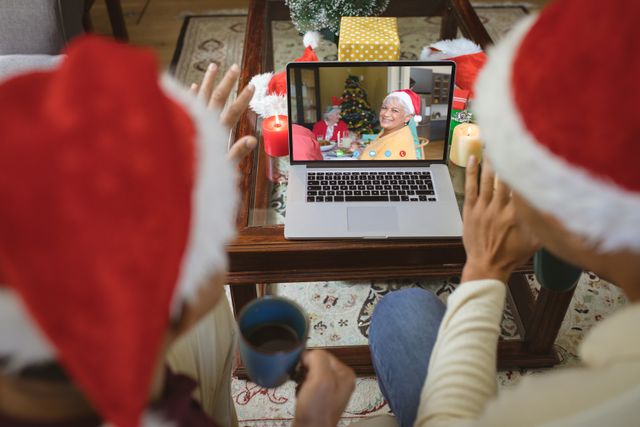 Diverse couple with santa hats having video call with happy biracial family. Christmas, celebration and digital composite image.