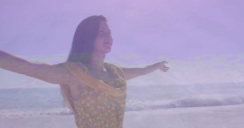 Woman in yellow dress enjoying ocean breeze on beach