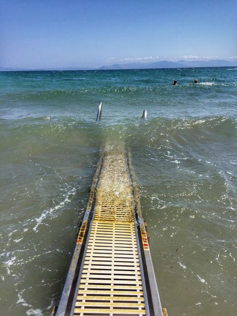 Water Ramp Extending into Calm Blue Sea with Swimmers in Distance - Download Free Stock Images Pikwizard.com