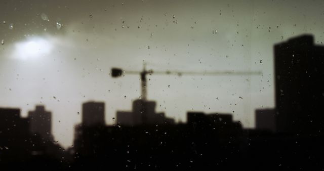 Rainy Cityscape with Silhouette of Construction Crane at Sunset - Download Free Stock Images Pikwizard.com