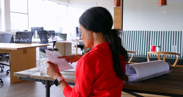 Professional Woman in Red Analyzing Documents in Modern Office - Download Free Stock Images Pikwizard.com