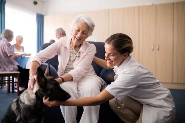 Portrait of smiling female doctor kneeling by senior woman stroking puppy at retirement home