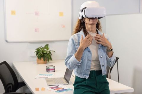 Mature professional woman experiencing virtual reality in modern office meeting room