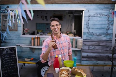 Cheerful Man Enjoying Food and Drink at Outdoor Food Truck Event