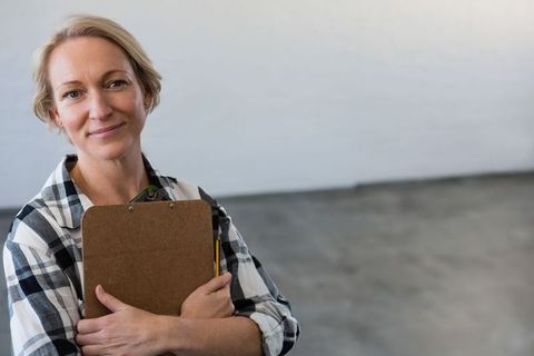 Confident Professional Woman Holding Clipboard in Empty Studio