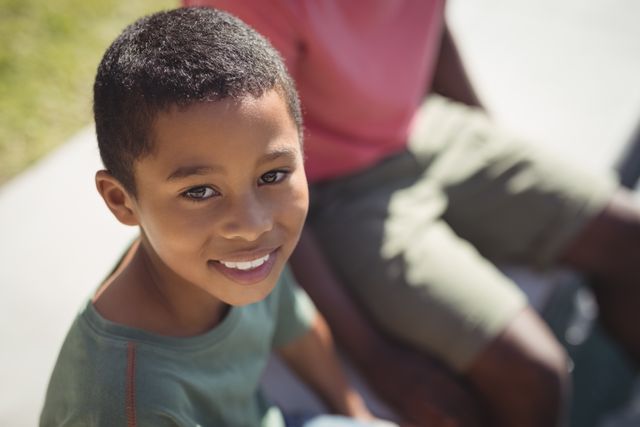 This image captures a close-up of a smiling boy looking directly at the camera while outdoors. The boy's cheerful expression and casual clothing make this photo perfect for use in advertisements, educational materials, and family-oriented content. It can also be used in articles or blogs discussing childhood, happiness, and outdoor activities.