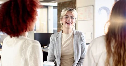 Diverse Female Coworkers Engaging in Office Discussion with Coffee