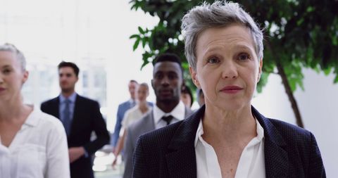 Senior Businesswoman Leading Corporate Team Through Lobby